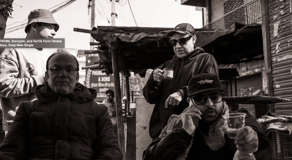 Pataka Boys in India with an elderly man, all looking straight into the camera.